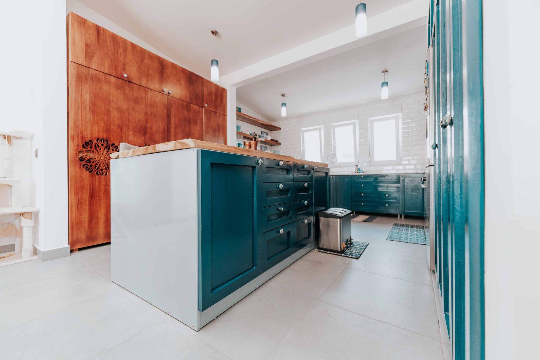 A spacious modern kitchen with blue cabinets and wood accents, featuring ambient lighting.