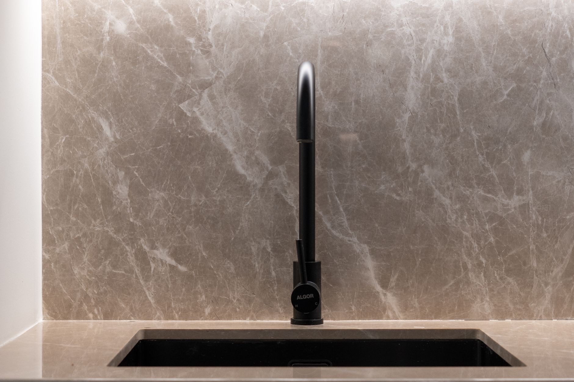 A stylish kitchen sink with a marble backsplash and black faucet. Ideal for modern home designs.