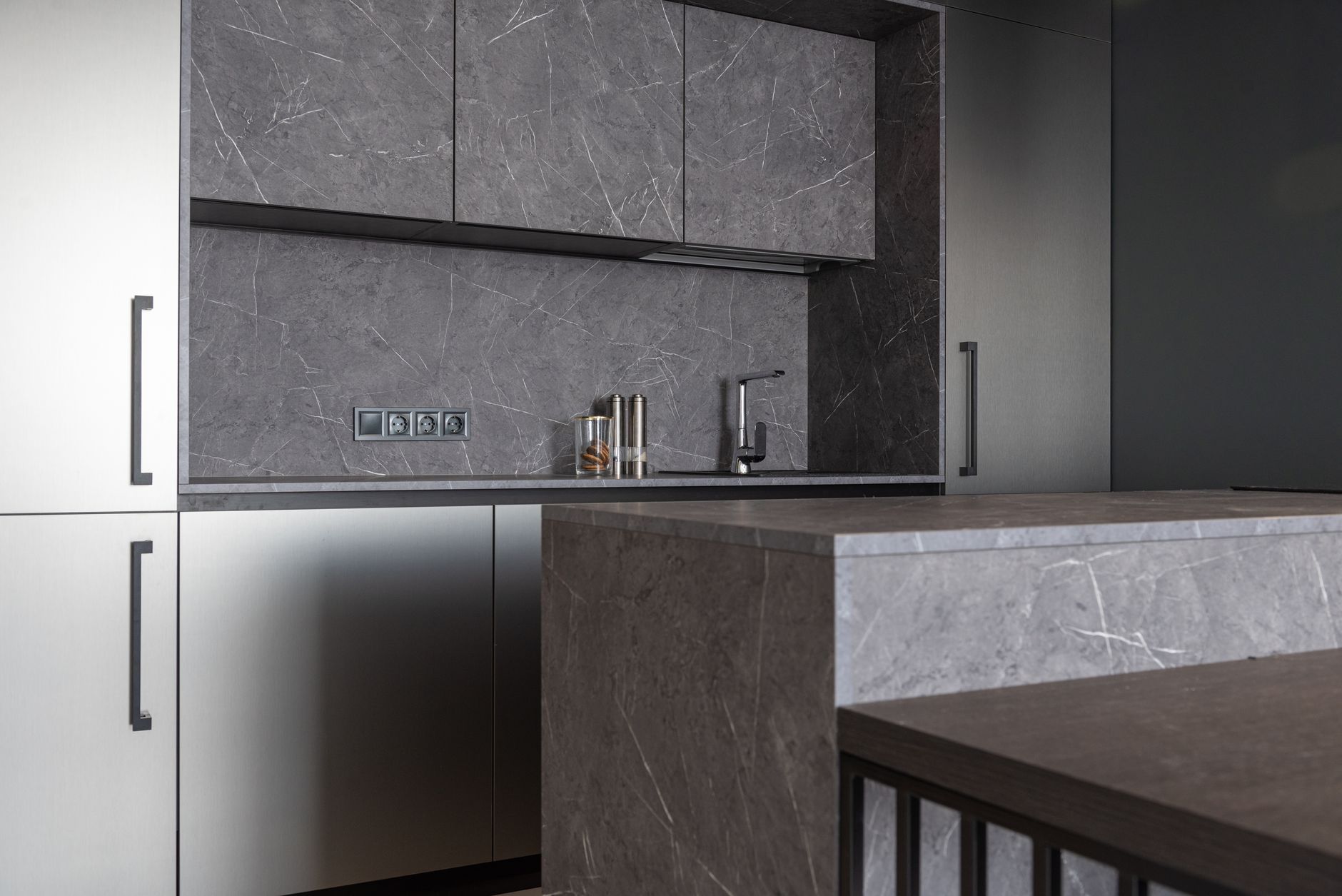 Interior of contemporary kitchen with minimalist gray furniture and counter in residential apartment