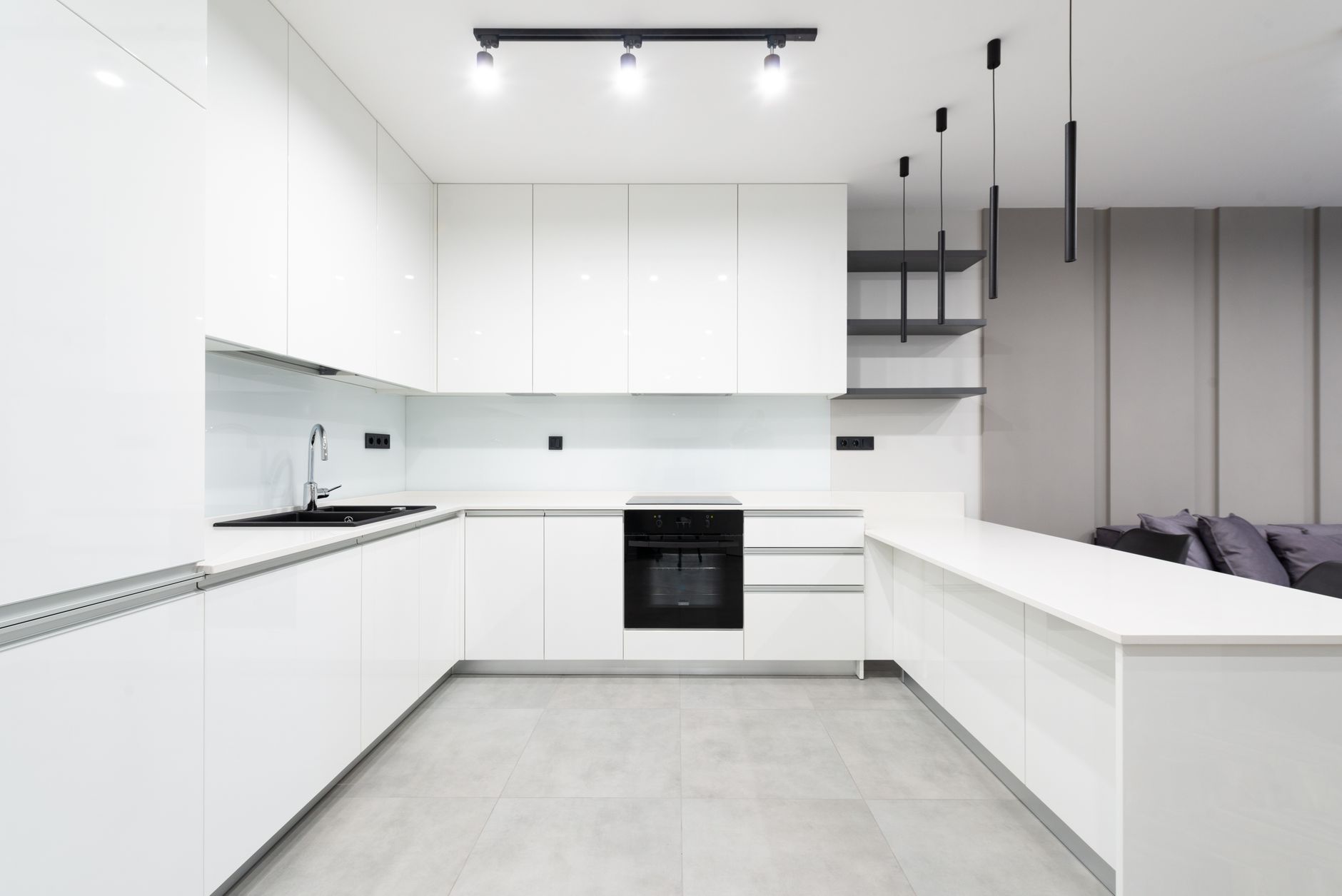 Elegant white minimalist kitchen featuring sleek cabinetry and modern lighting.