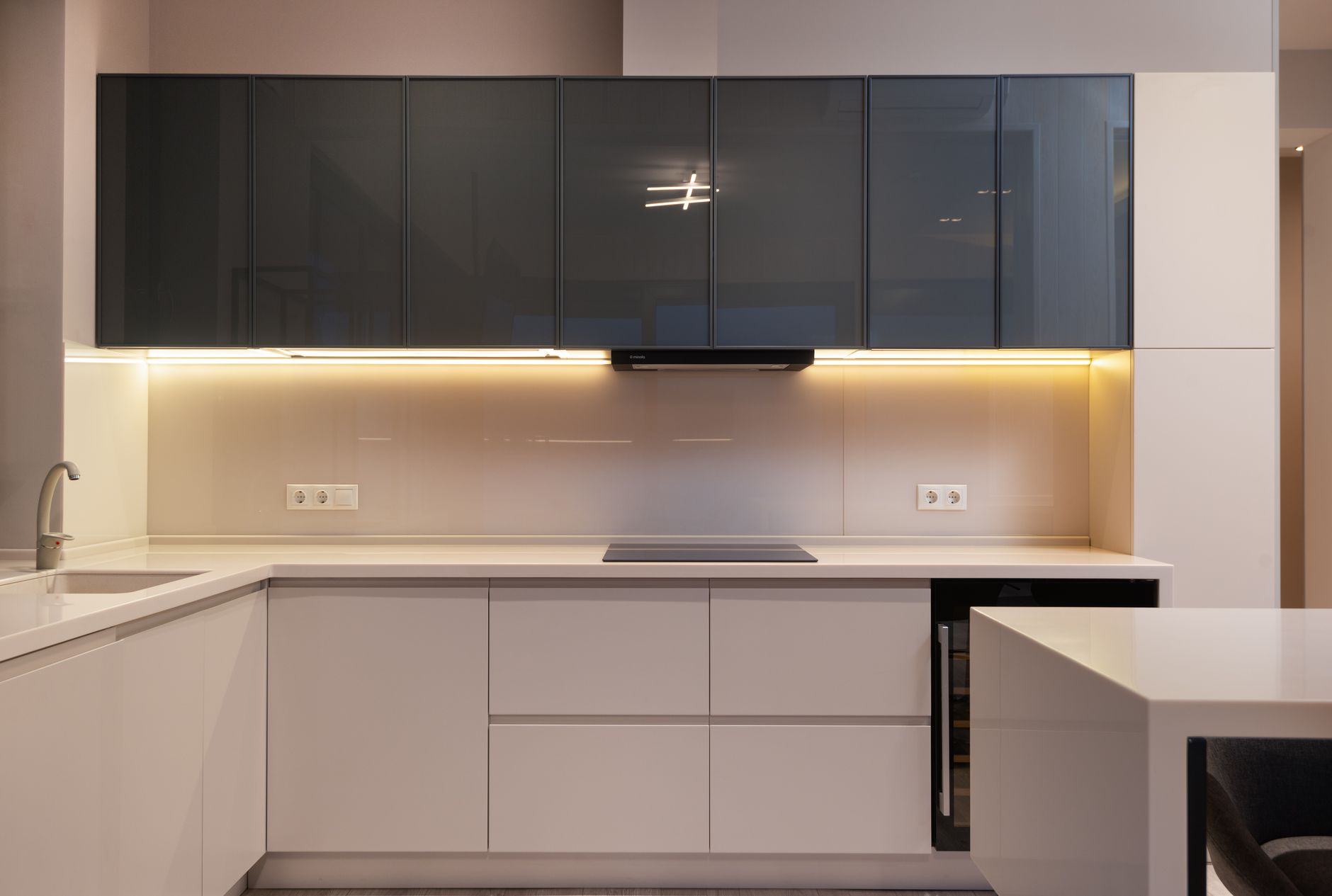 Interior of modern light kitchen with minimalist furniture and illumination in spacious apartment