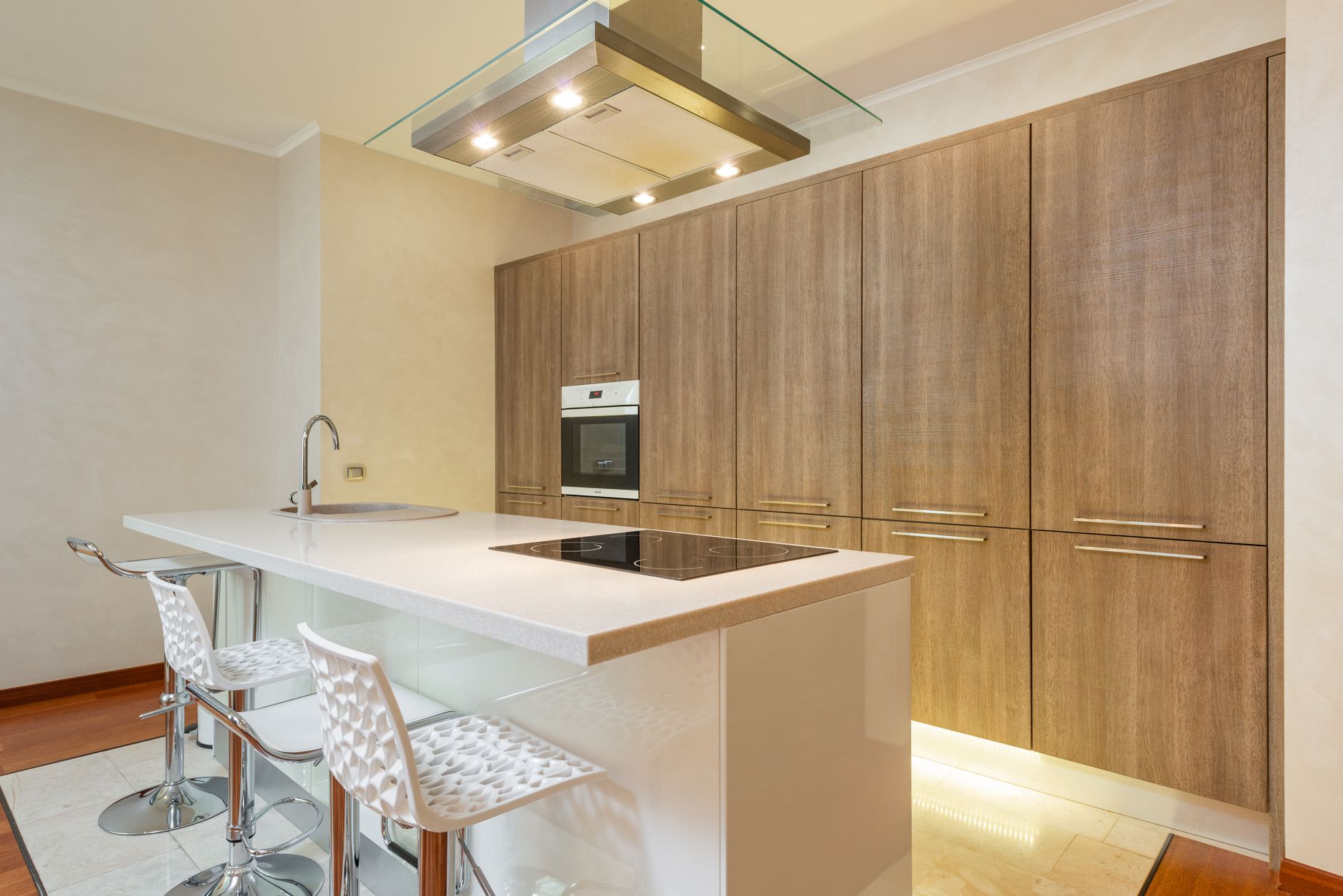 Interior of contemporary illuminated kitchen with minimalist styled furniture and built in appliances in spacious apartment