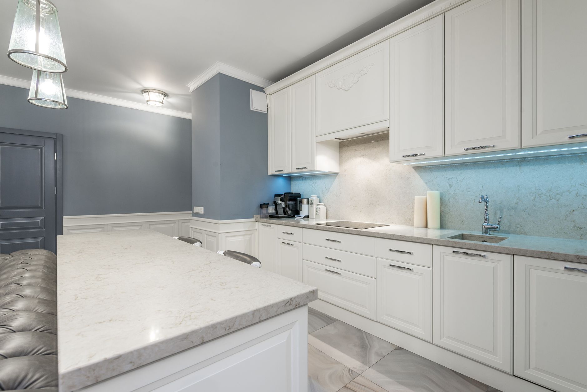 Sleek modern kitchen design featuring white cabinets, marble countertop, and ambient lighting for a minimalist look.