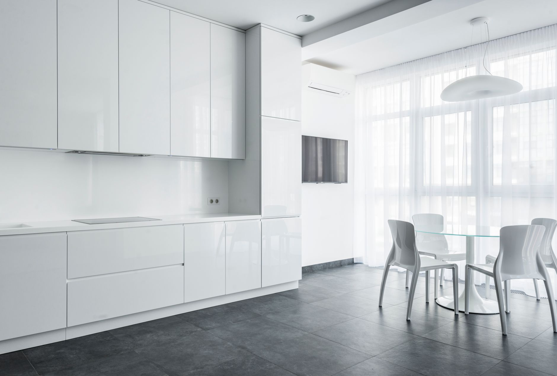 Bright and modern kitchen featuring sleek white cabinetry and elegant dining area.